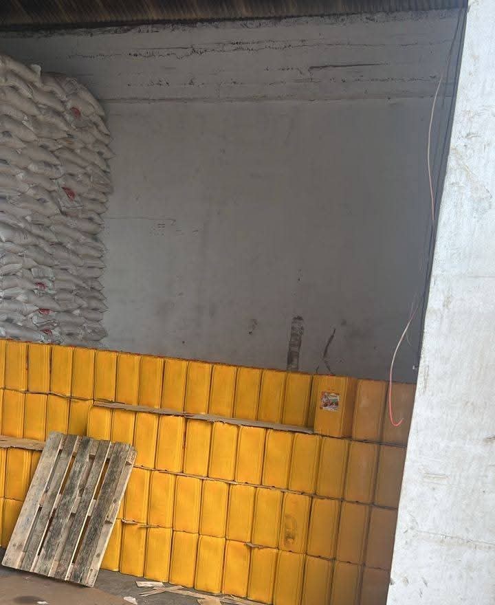Yellow containers stacked in a storeroom next to stacked sacks